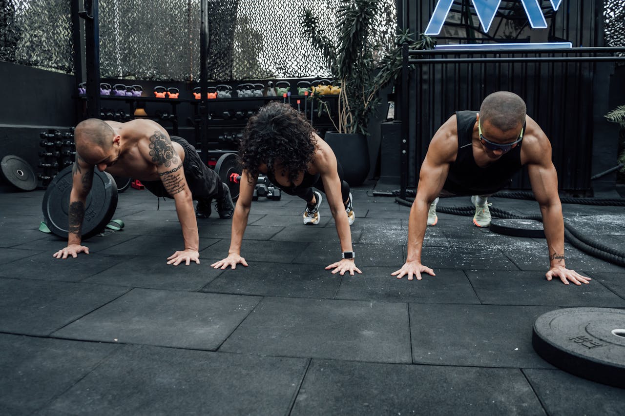 services-02 Three individuals performing push-ups together in a Mexico City gym setting.